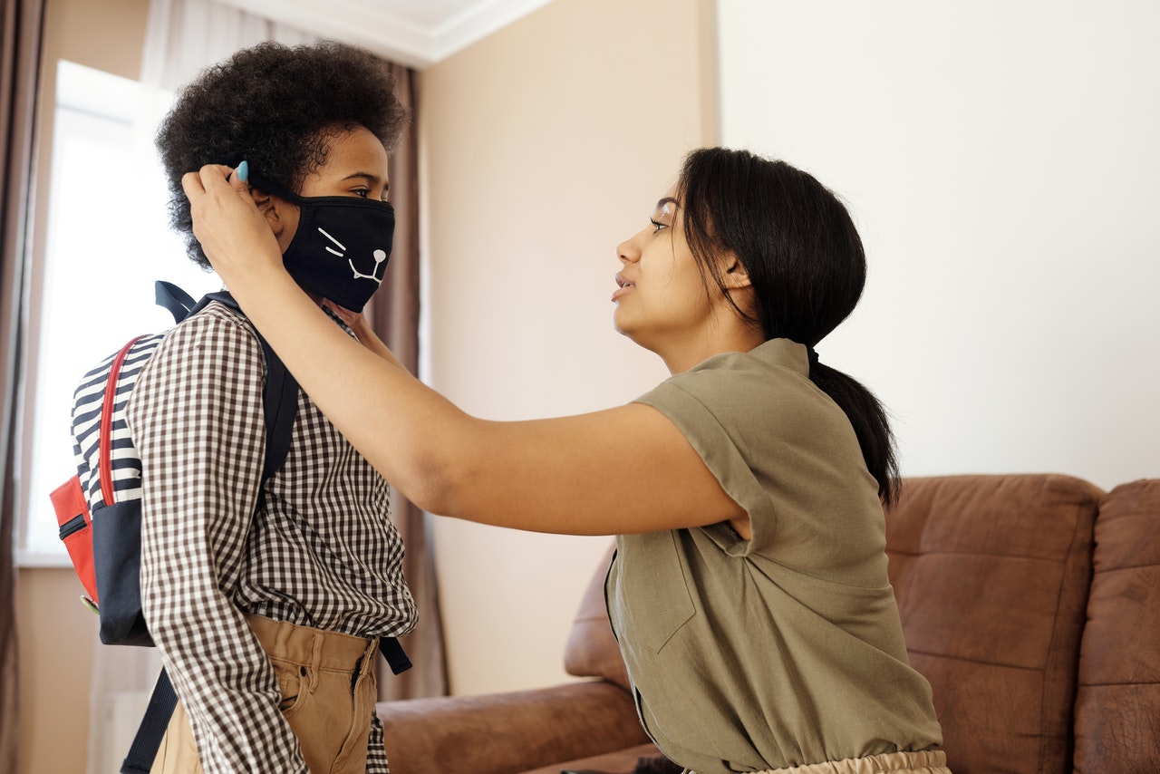 mother-putting-a-face-mask-on-her-son-4261265
